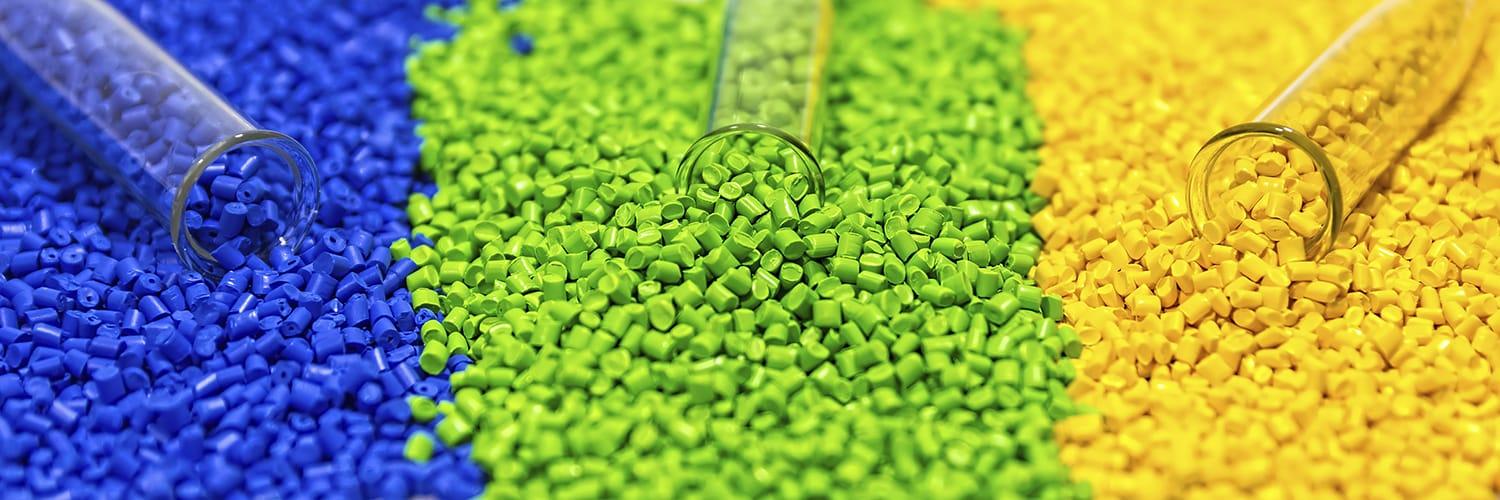 Polymer resin pellets in three colors being poured from glass test tubes